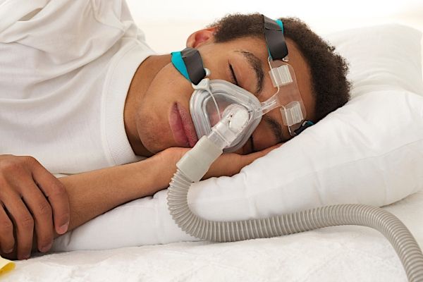 young mulatto man sleeping with apnea and CPAP machine
