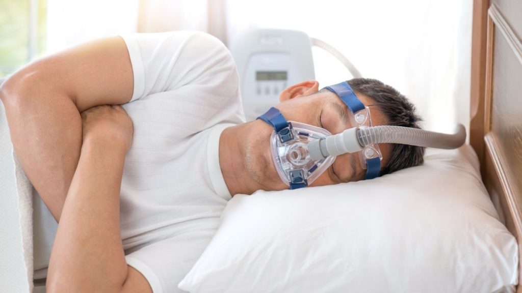 Man sleeping in bed wearing CPAP mask