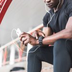 a black man resting after a workout and listening to music and watching a sports watch