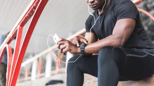 a black man resting after a workout and listening to music and watching a sports watch